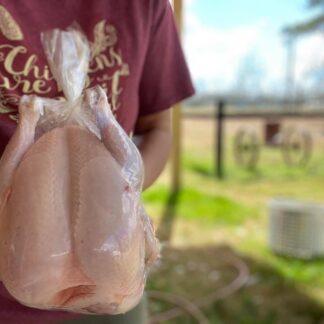 The chicken in the picture appears to have been recently butchered and is wrapped tightly in plastic. It's clear that the person holding the chicken is inspecting it closely, likely checking for any issues with the meat.