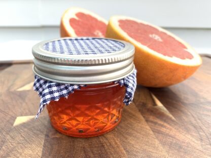Bright pink marmalade in a small quilted glass jar.